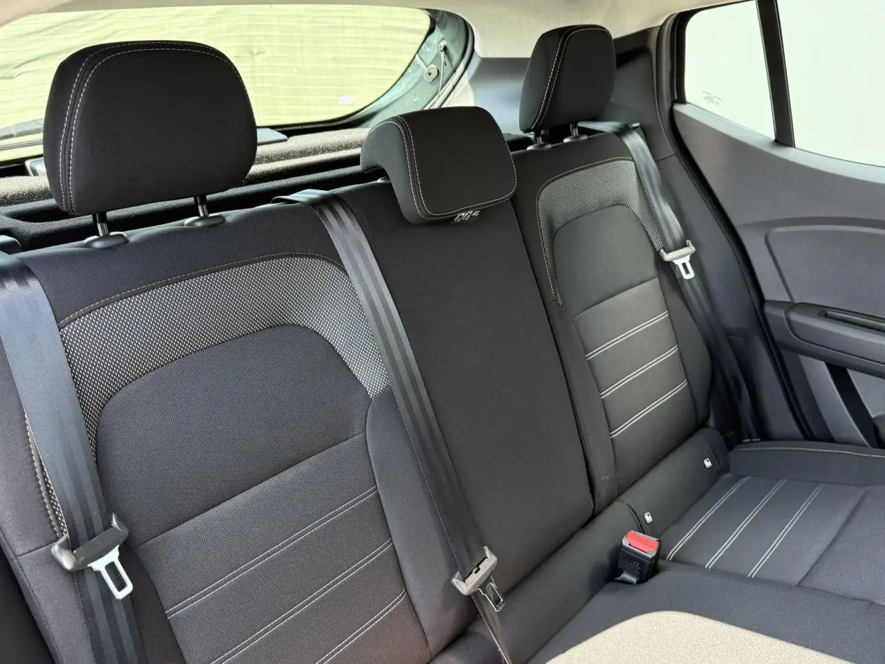 Vue intérieure de la banquette arrière noire avec appuie-têtes et ceintures de sécurité du Dacia Sandero Stepway 2025.