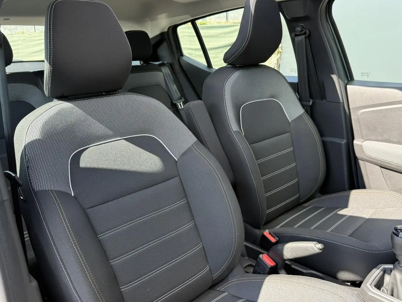 Gros plan sur les sièges avant noirs avec surpiqûres claires de la Dacia Sandero Stepway 2025, côté conducteur et passager.