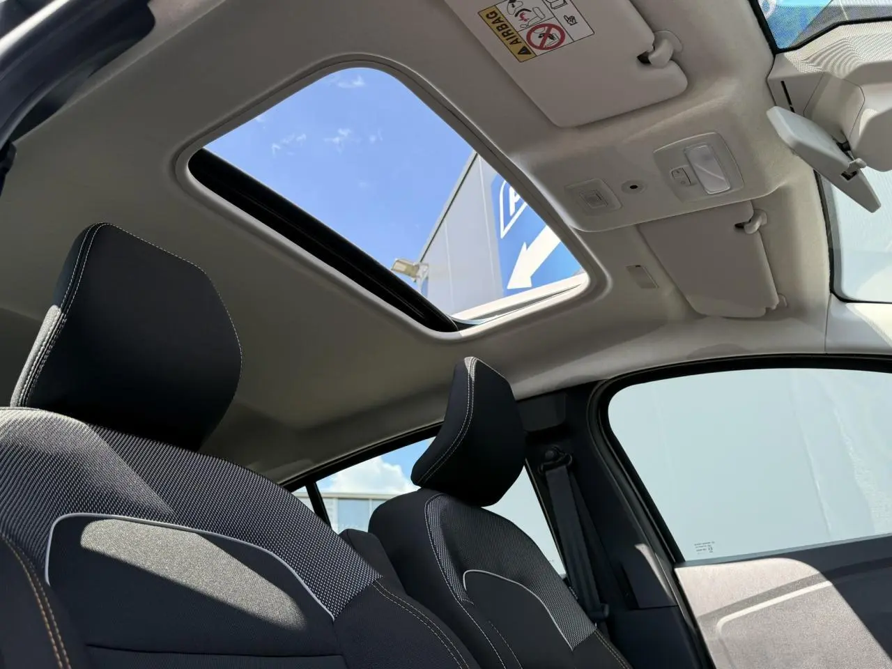 Vue intérieure avant de la Dacia Sandero Stepway 2025 avec toit ouvrant électrique et sièges noirs à surpiqûres blanches