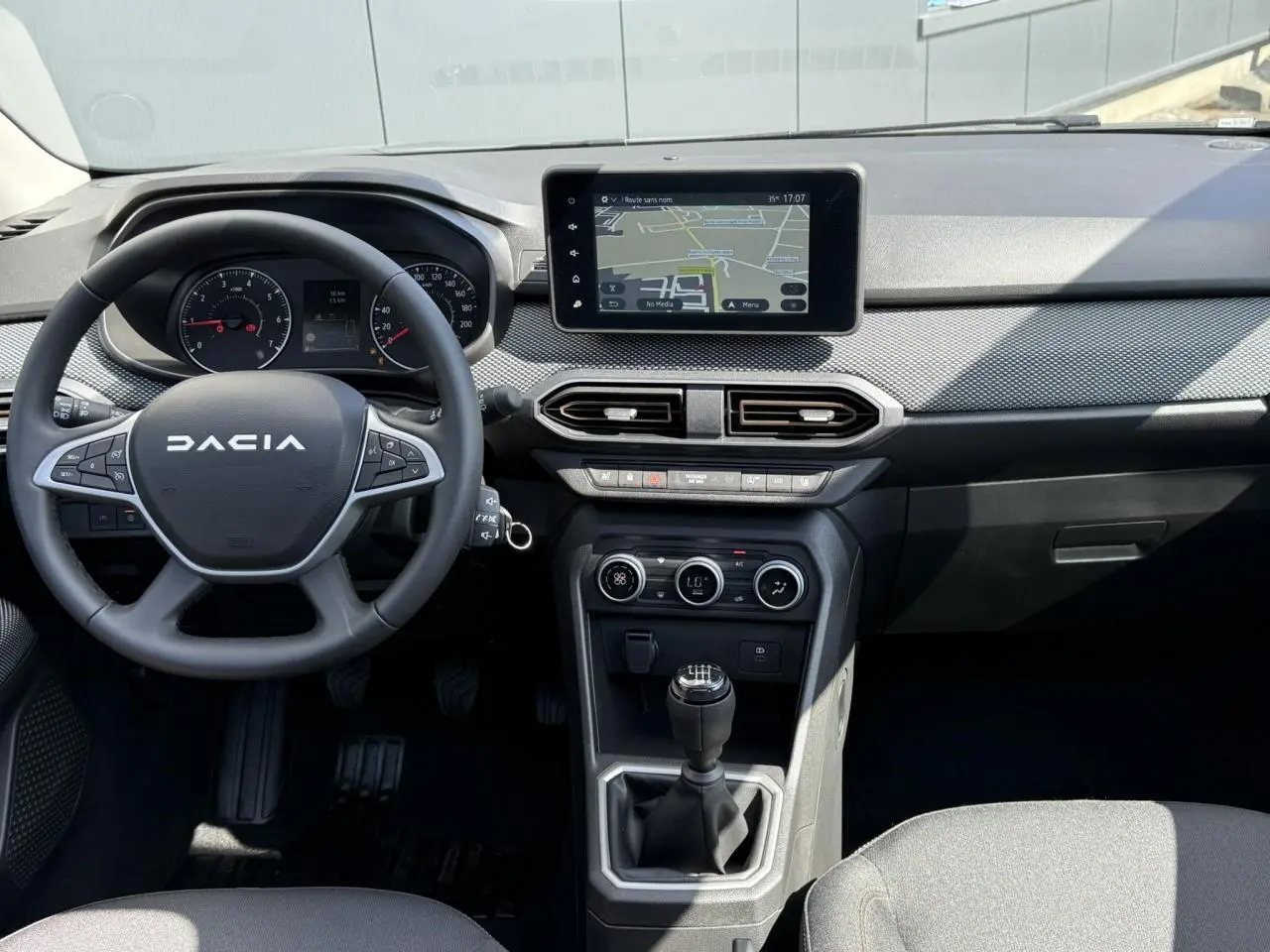Vue intérieure centrée sur le tableau de bord et volant du Dacia Sandero Stepway 2025 avec écran tactile et boîte manuelle.