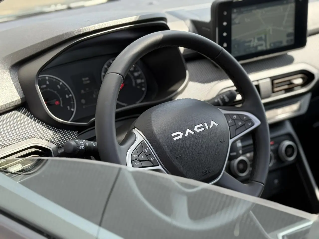 Vue rapprochée du volant Dacia et du tableau de bord numérique du Sandero Stepway 2025, ambiance intérieure moderne.