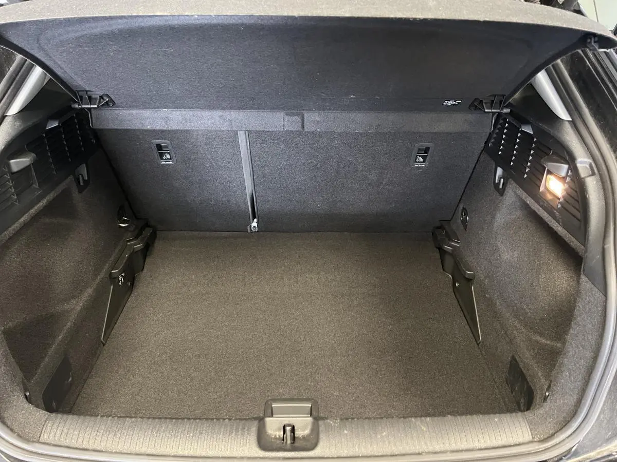 Coffre ouvert de l'Audi Q2 2023 noir, vue arrière montrant l'espace de chargement et l'éclairage intérieur à droite.