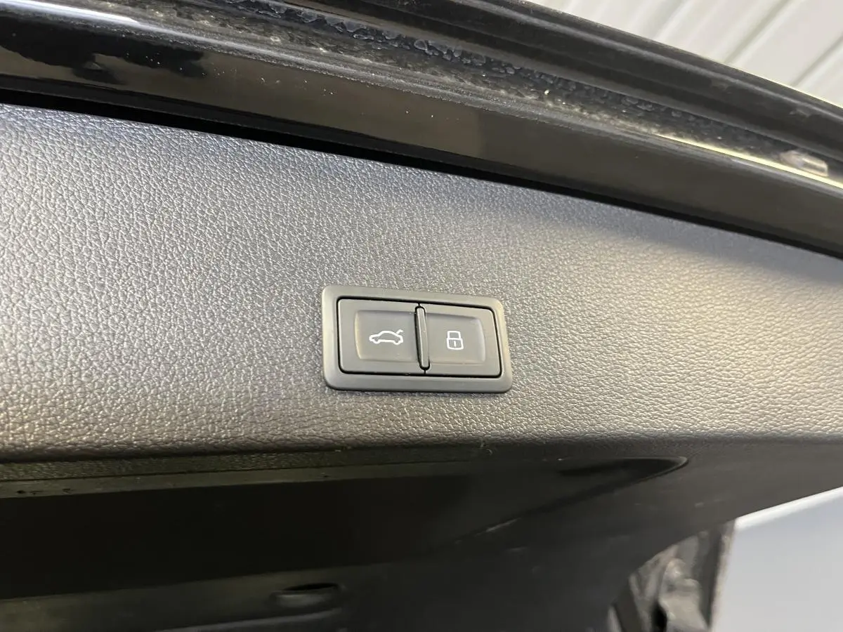 Boutons d'ouverture et de verrouillage du coffre sur la garniture intérieure du hayon noir d'un Audi Q2 2023.