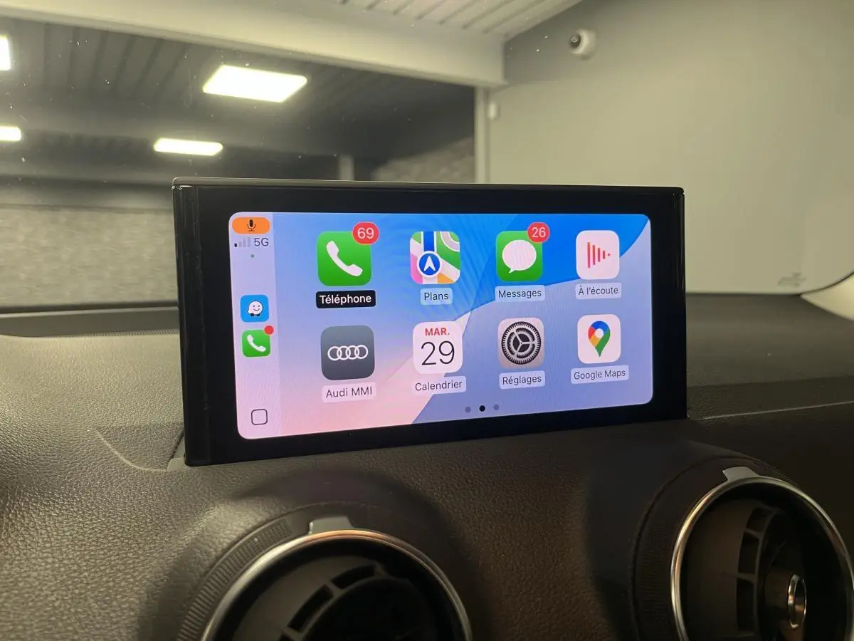 Écran tactile central affichant l'interface Apple CarPlay dans l'habitacle d'un Audi Q2 noir 2023.