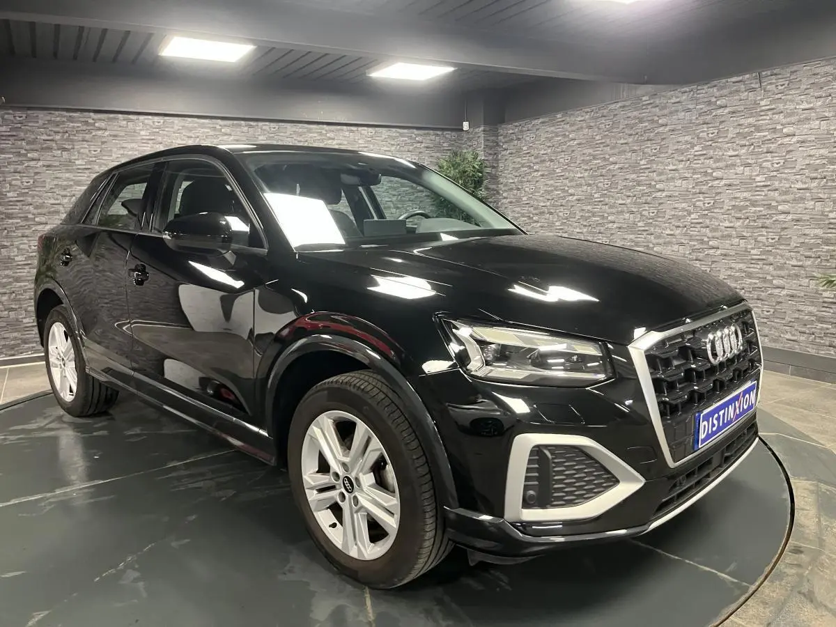 Audi Q2 2023 noir brillant vue 3/4 avant droit avec calandre hexagonale et jantes 5 branches doubles.