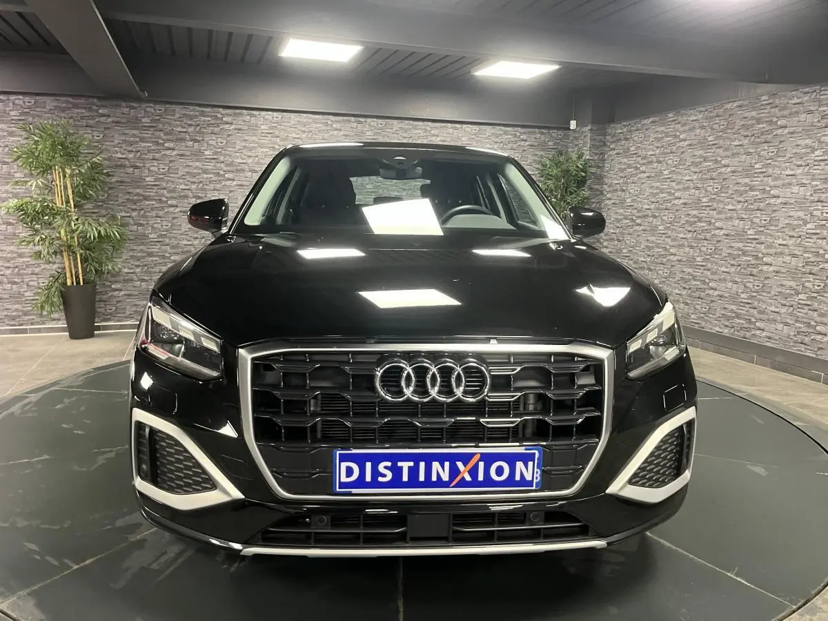 Audi Q2 noir brillant vue de face dans un showroom avec calandre hexagonale et éclairage LED distinctif.