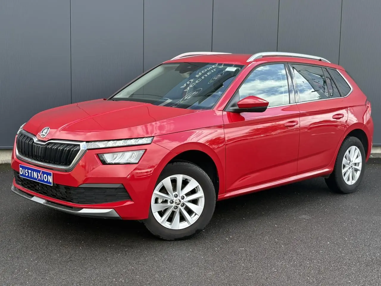 SKODA KAMIQ rouge Velvet en 3/4 avant droit, avec jantes alliage et barres de toit argentées visibles.