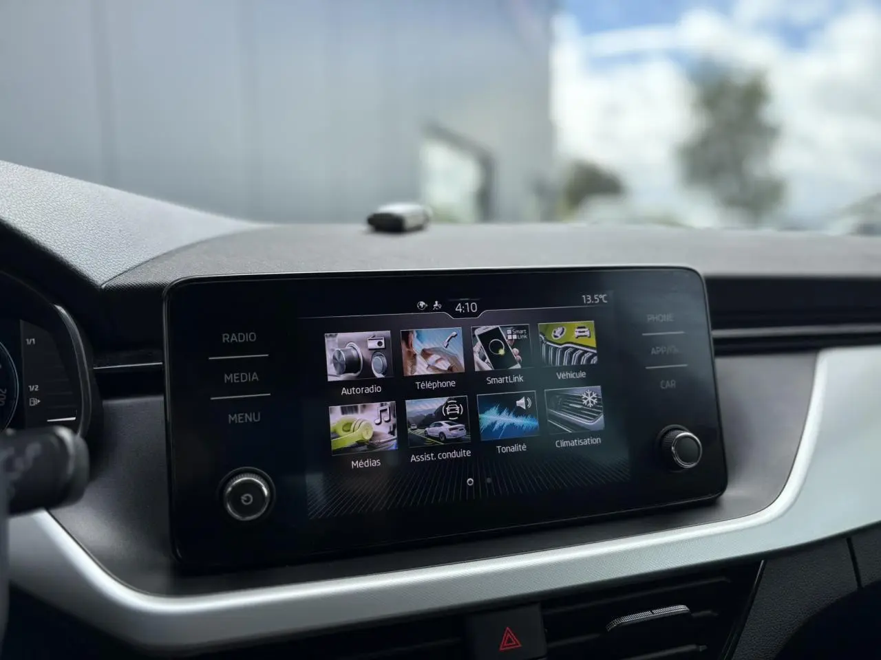 Écran tactile central du Skoda Kamiq 2024 affichant les menus multimédia et assistance à la conduite, vue intérieure frontale.