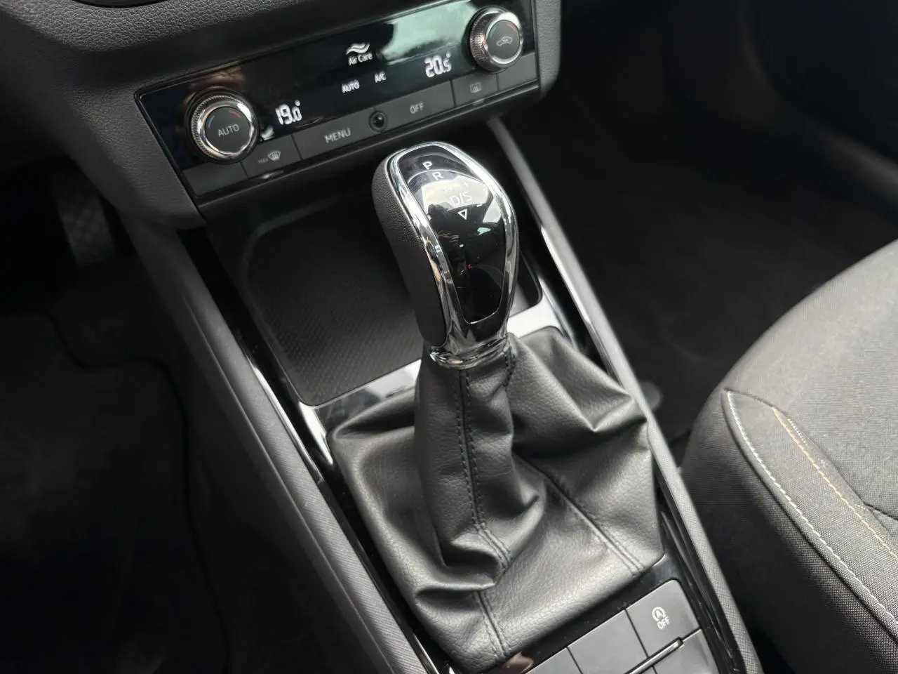 Le levier de vitesse automatique noir et chrome du Skoda Kamiq TSI 110 DSG Ambition vu de dessus avec console et siège gris.