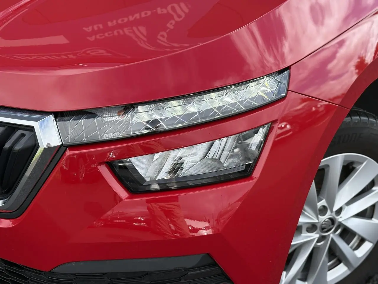 Gros plan sur le phare avant droit du SKODA KAMIQ Rouge Velvet 2024 avec jante alliage et calandre chromée.