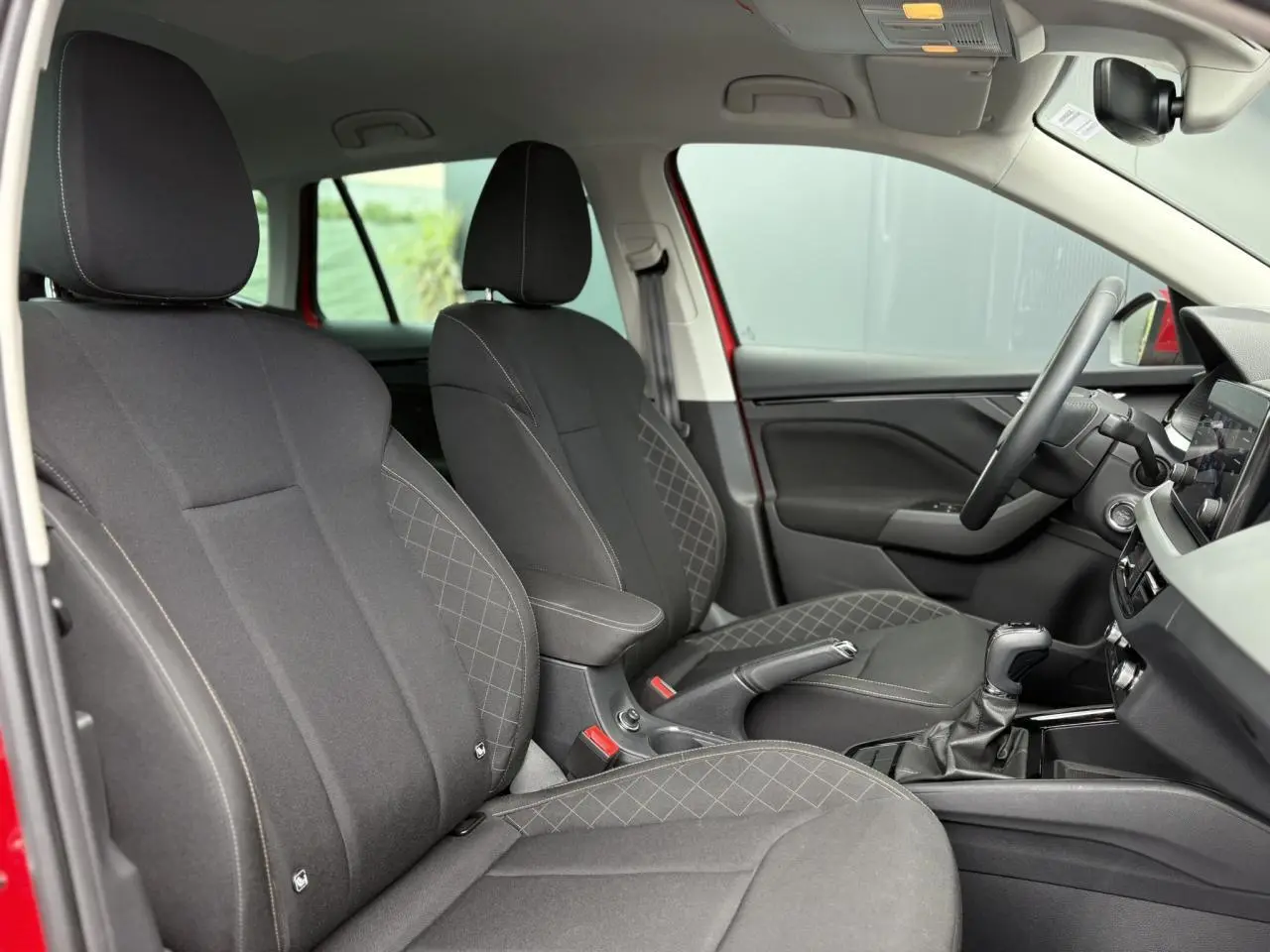 Intérieur du Skoda Kamiq rouge Velvet, vue côté droit sur les sièges tissu noirs et console centrale avec boîte auto.