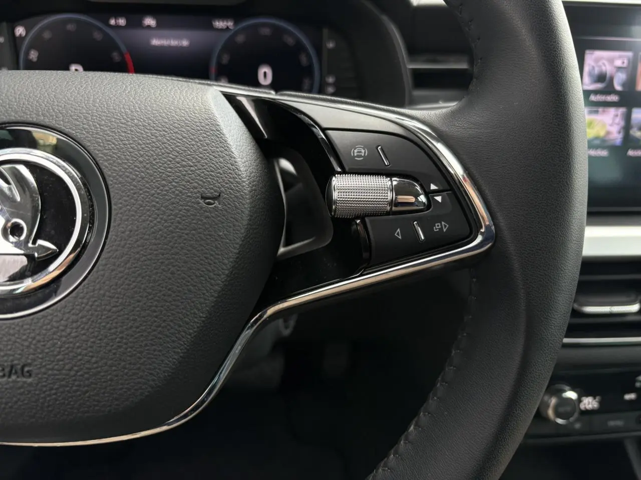 Gros plan sur le volant cuir noir du Skoda Kamiq 2024 avec commandes multifonctions et cadrans numériques en arrière-plan.