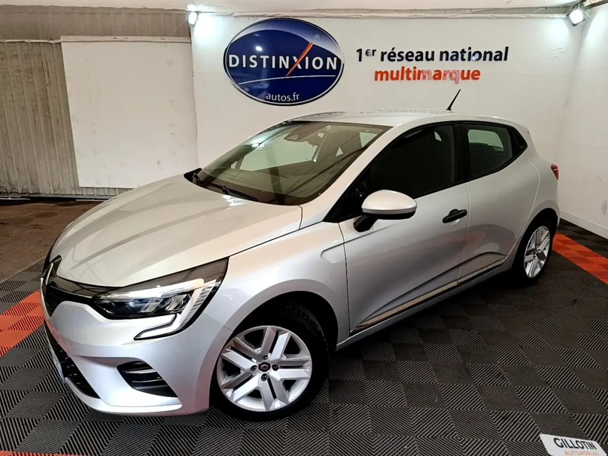 Renault Clio Business TCe 100 gris clair vue 3/4 avant droit dans un showroom avec logo Distinxion en arrière-plan