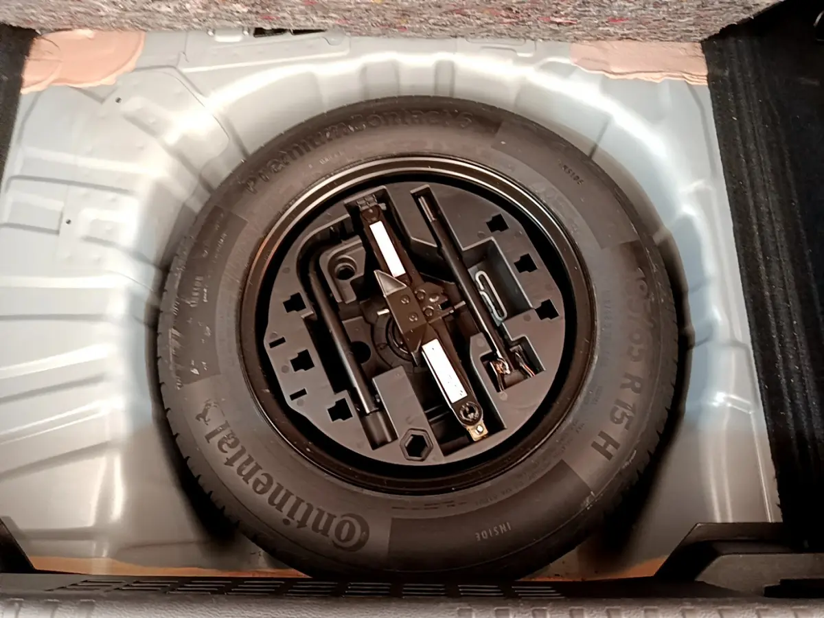 Gros plan sur la roue de secours et les outils de bord dans le coffre d'une Renault Clio Business TCe 100 gris clair.