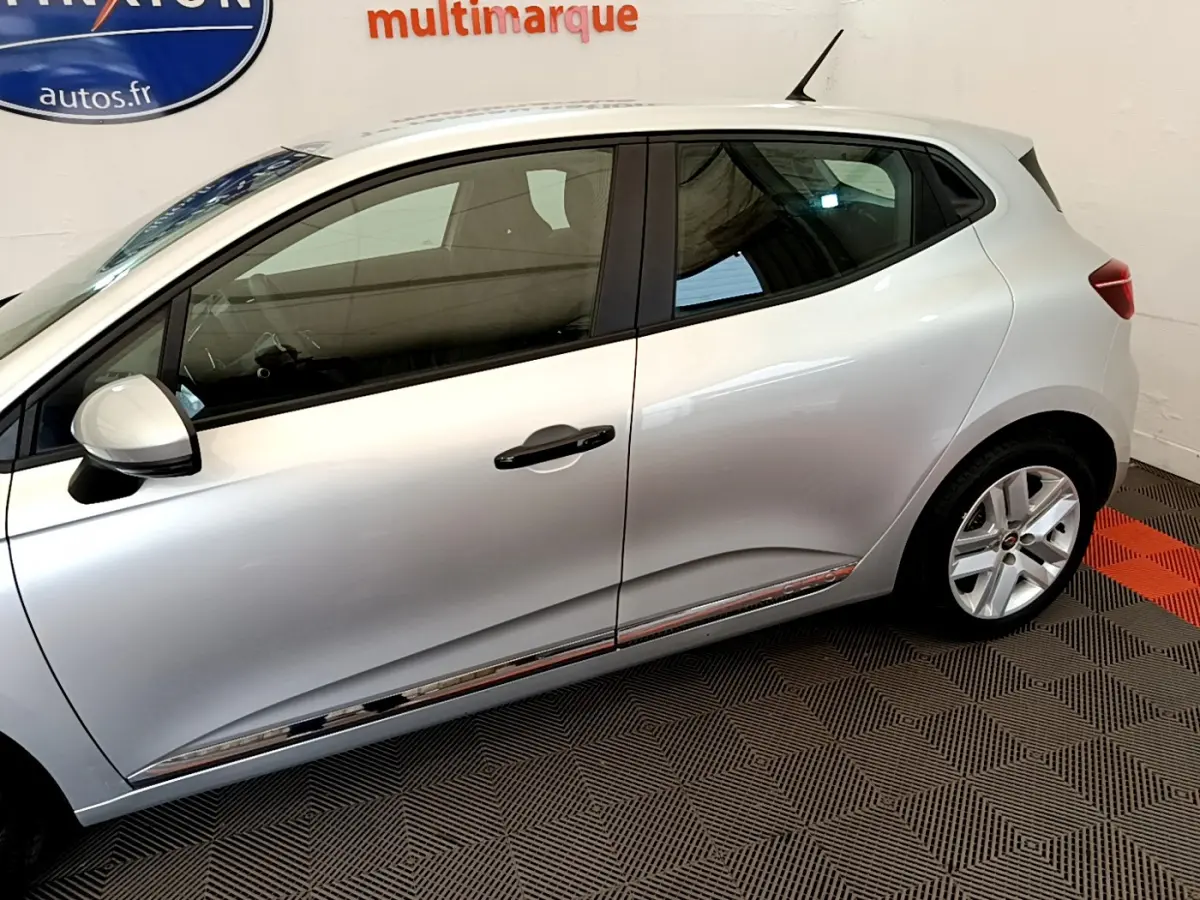 Profil côté gauche de la Renault Clio Business TCe 100 gris clair, avec jantes alliage et poignées noires visibles.