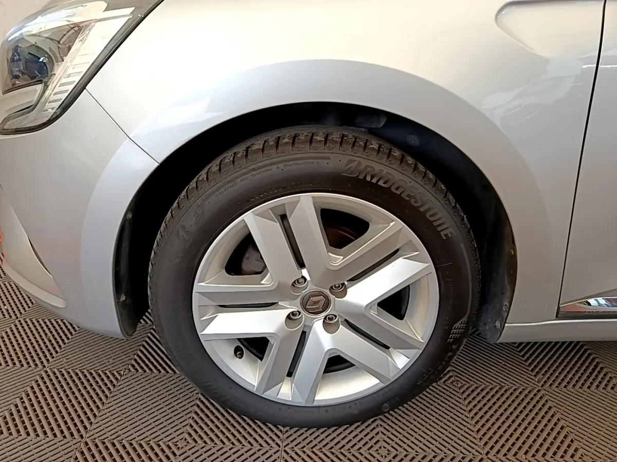 Gros plan sur la roue avant gauche d'une Renault Clio Business gris clair, avec jante alliage et pneu Bridgestone.