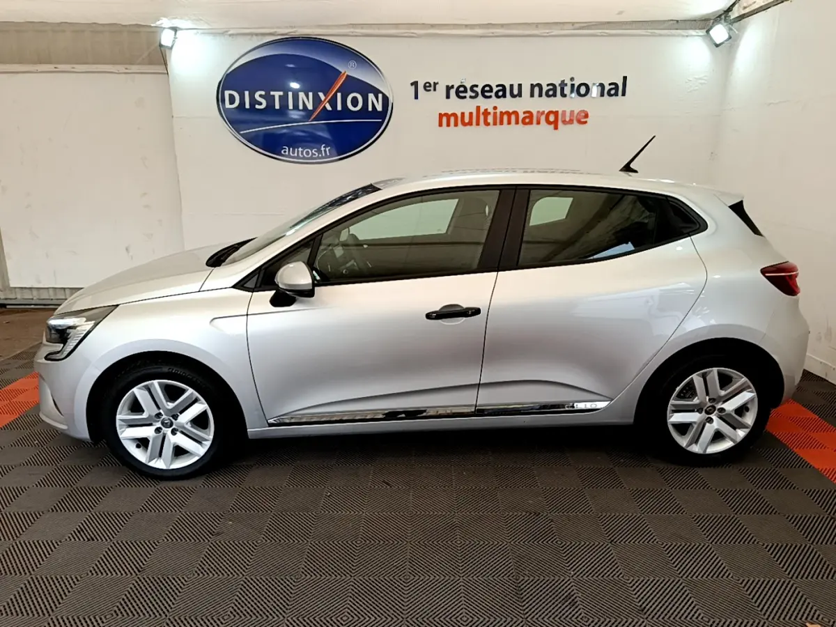 Profil côté gauche d'une Renault Clio Business TCe 100 gris clair, vue en intérieur sur fond de logo Distinxion.