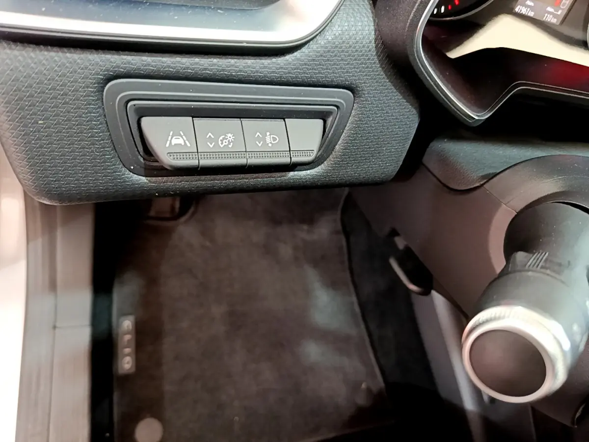 Gros plan sur les commandes d'assistance au conducteur à gauche du volant d'une Renault Clio Business TCe 100 gris clair de 2020.