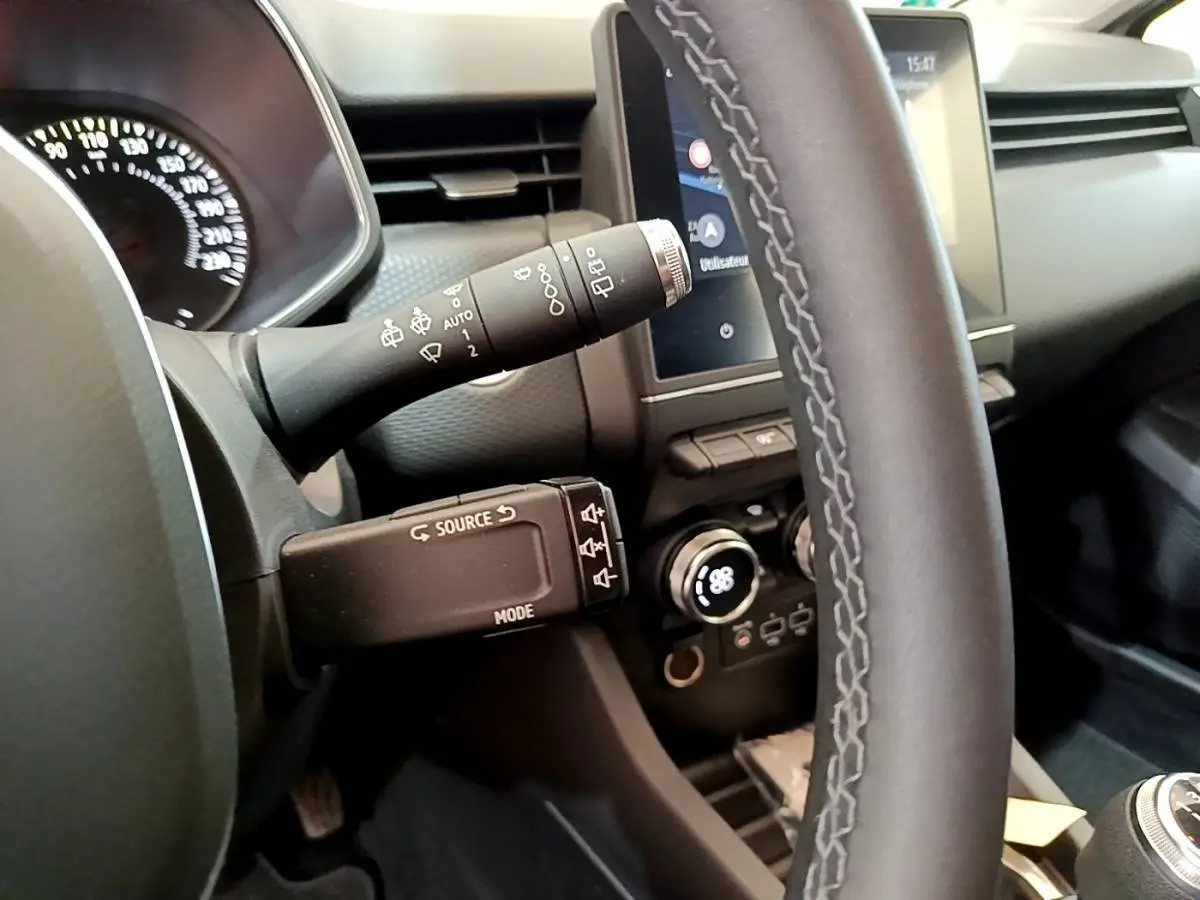 Vue rapprochée du volant et commandes du tableau de bord d'une Renault Clio Business TCe 100 gris clair, avec écran tactile.