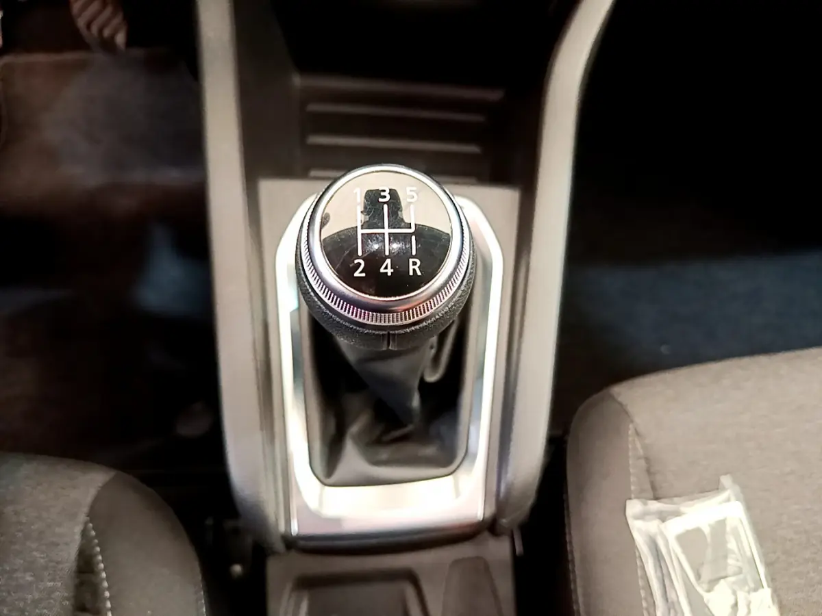 Le levier de vitesses manuel noir de la Renault Clio Business TCe 100 2020, vu de dessus entre les sièges gris.