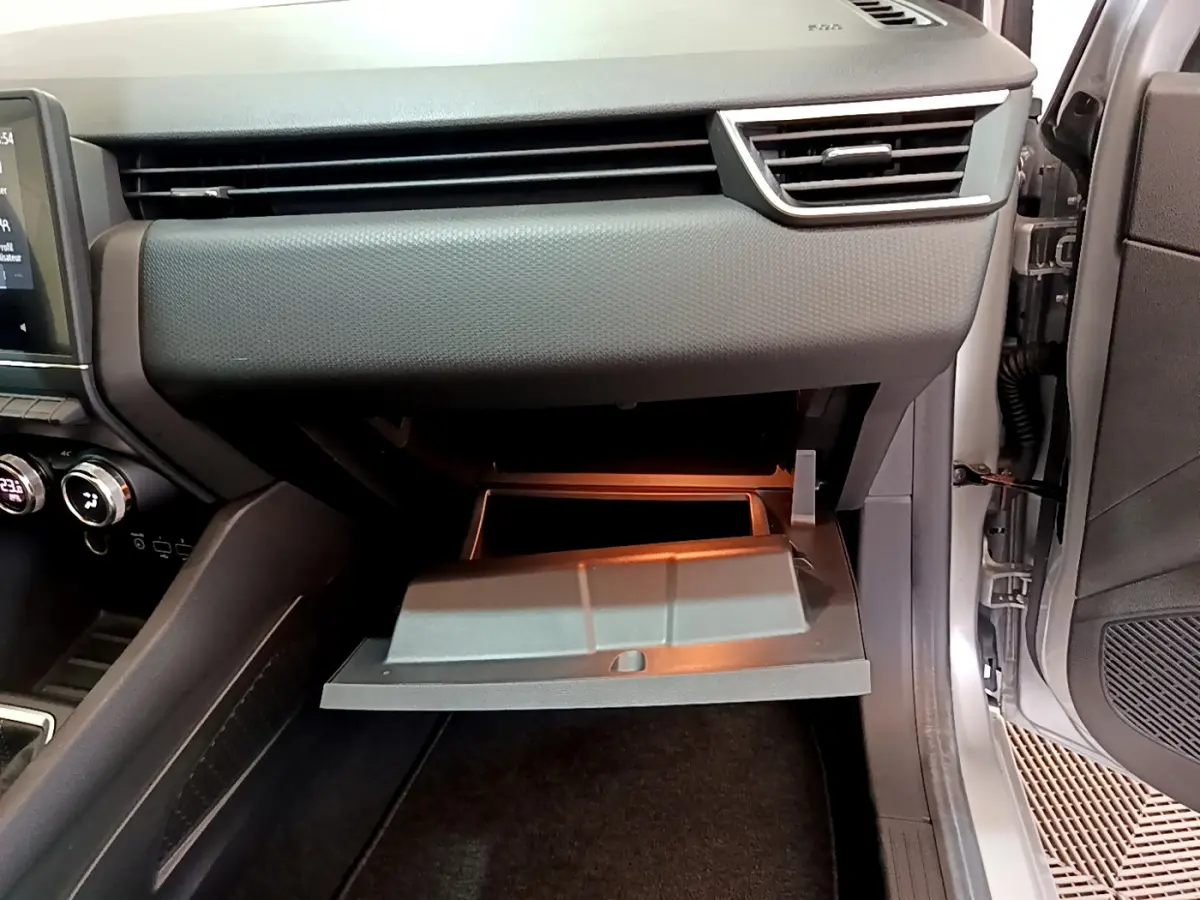 Vue intérieure côté passager de la Renault Clio Business TCe 100 2020 gris clair, boîte à gants ouverte et tableau de bord moderne.