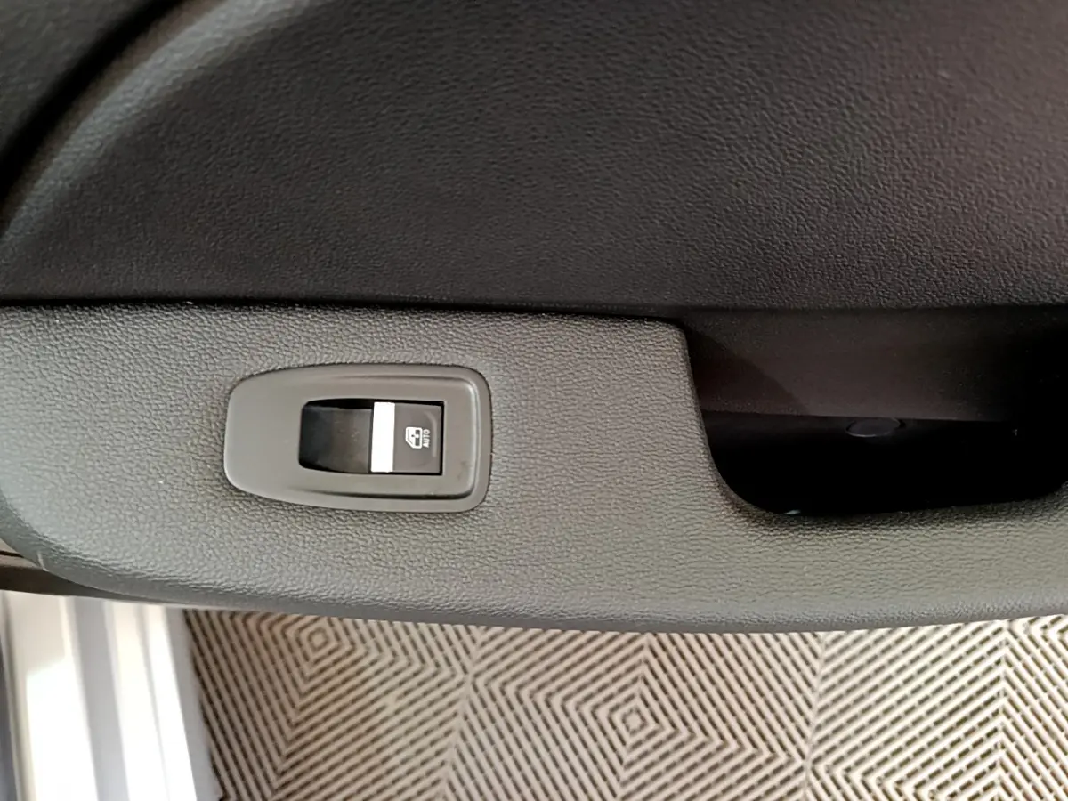 Bouton de commande de lève-vitre électrique sur la porte intérieure d'une Renault Clio Business gris clair.