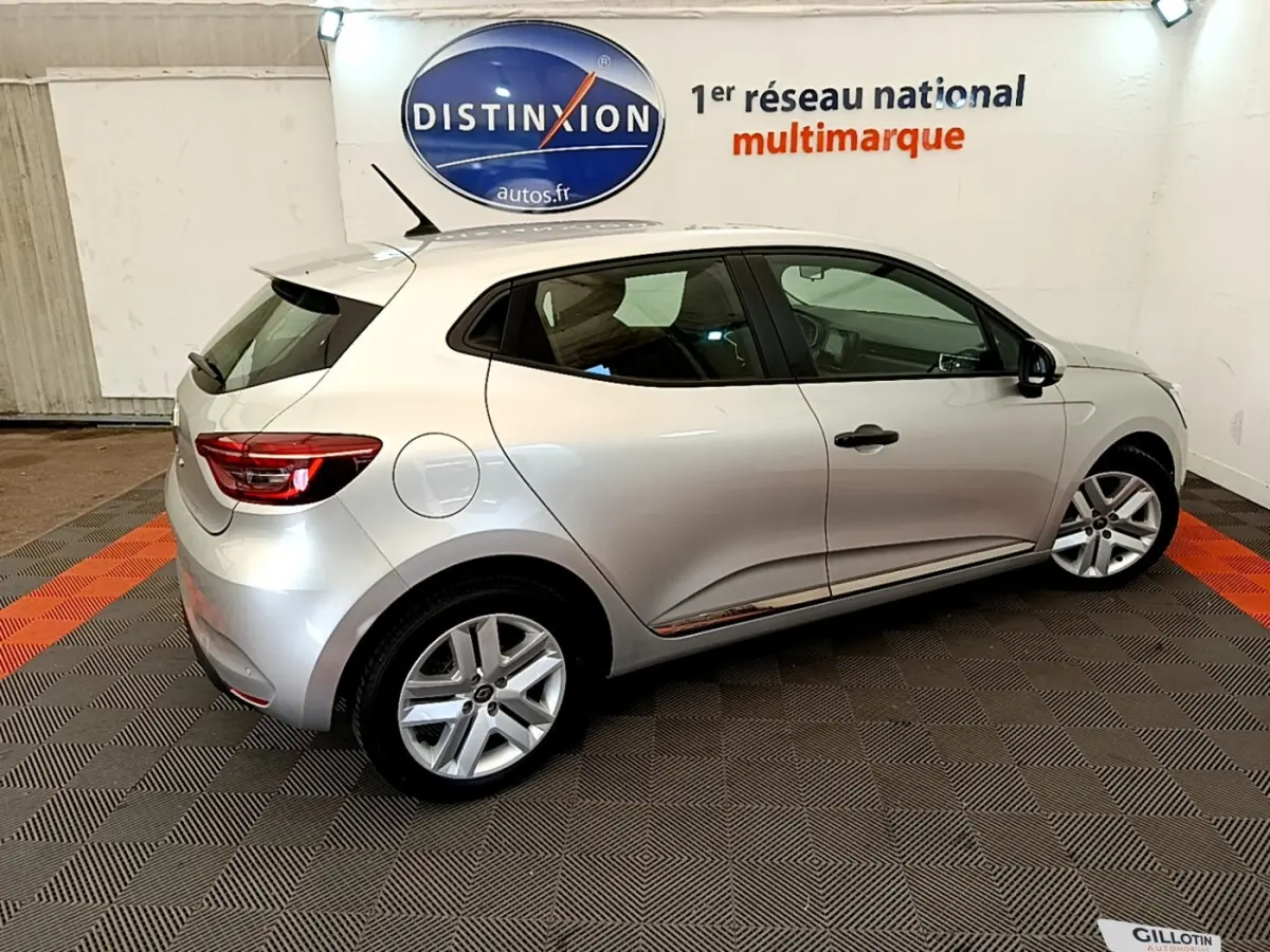 Renault Clio Business TCe 100 gris clair vue de profil côté gauche, stationnée en intérieur sur sol damier noir et orange.