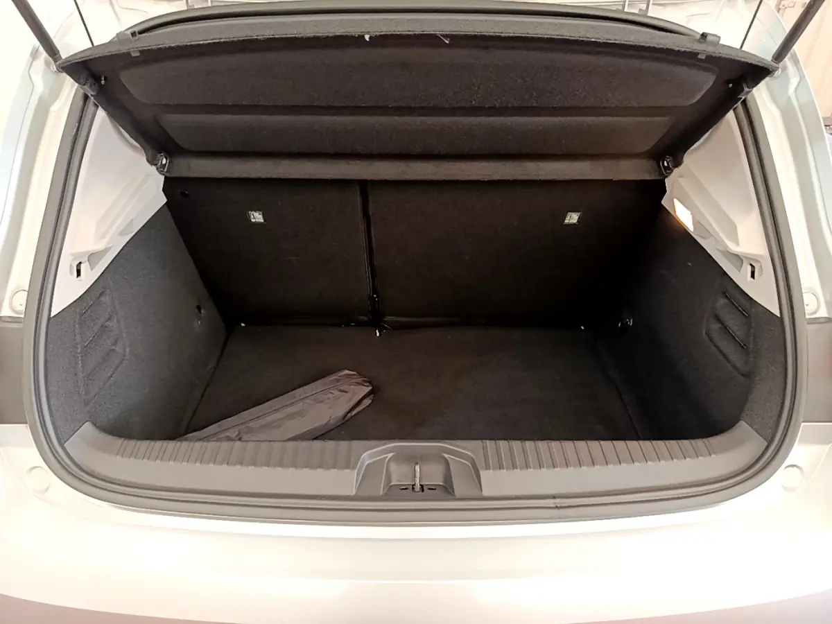 Coffre ouvert vu de l'arrière d'une Renault Clio Business TCe 100 gris clair, intérieur noir et espace de rangement vide.