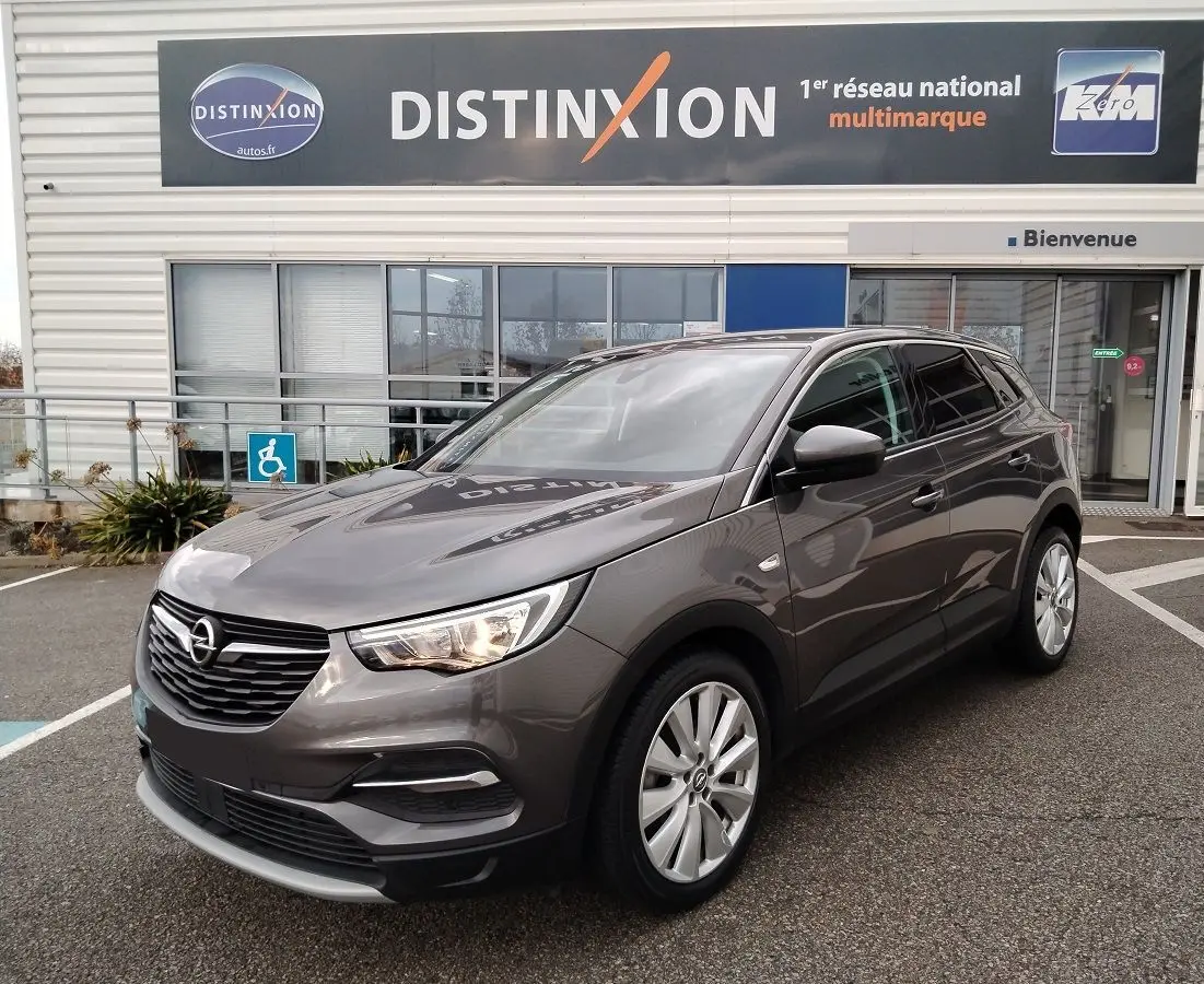 Opel Grandland X gris platinium vu en 3/4 avant droit, avec calandre noire et jantes alliage argentées.