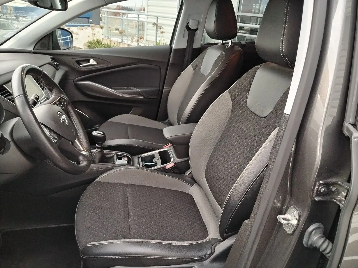 Vue intérieure côté conducteur de l'Opel Grandland X gris platinium, sièges tissu et cuir noir avec coutures contrastées.