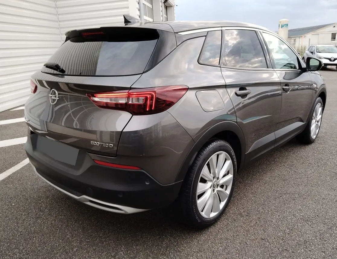 Vue 3/4 arrière droite d'un Opel Grandland X gris platinium avec feux LED et jantes alliage.