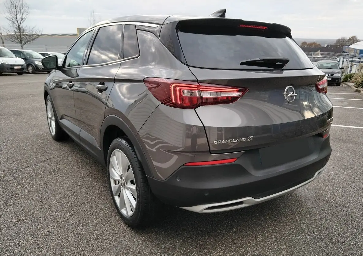 Vue 3/4 arrière droite d'un Opel Grandland X gris platinium avec feux arrière LED et jantes alliage.