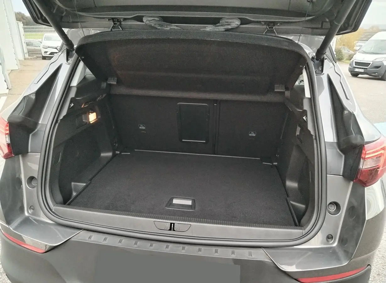 Coffre ouvert d'un Opel Grandland X gris platinium vu de l'arrière, montrant un espace de chargement propre et spacieux.