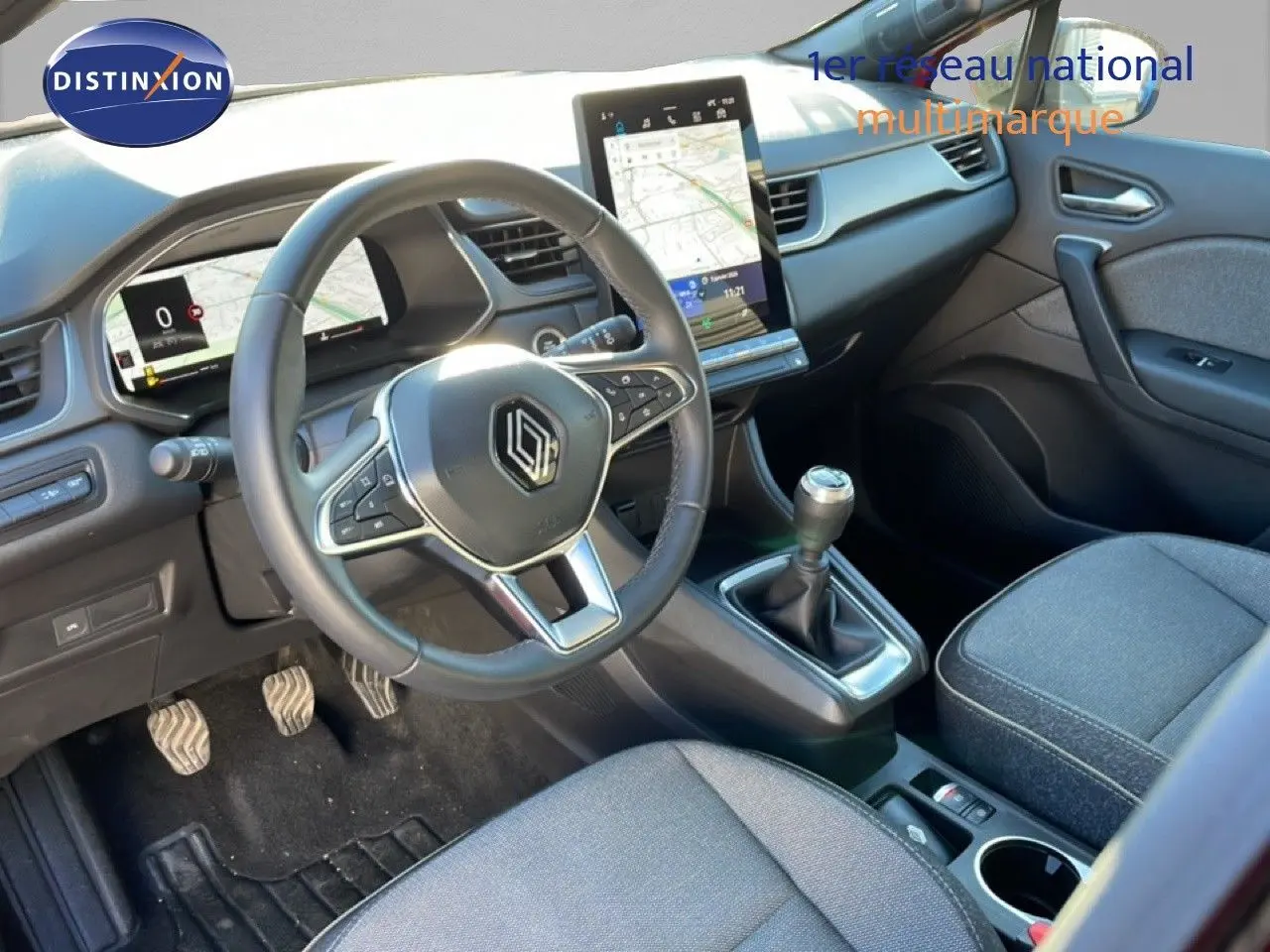 Vue intérieure avant droite du Renault Captur 2025, volant cuir, tableau de bord digital et console centrale avec boîte manuelle.
