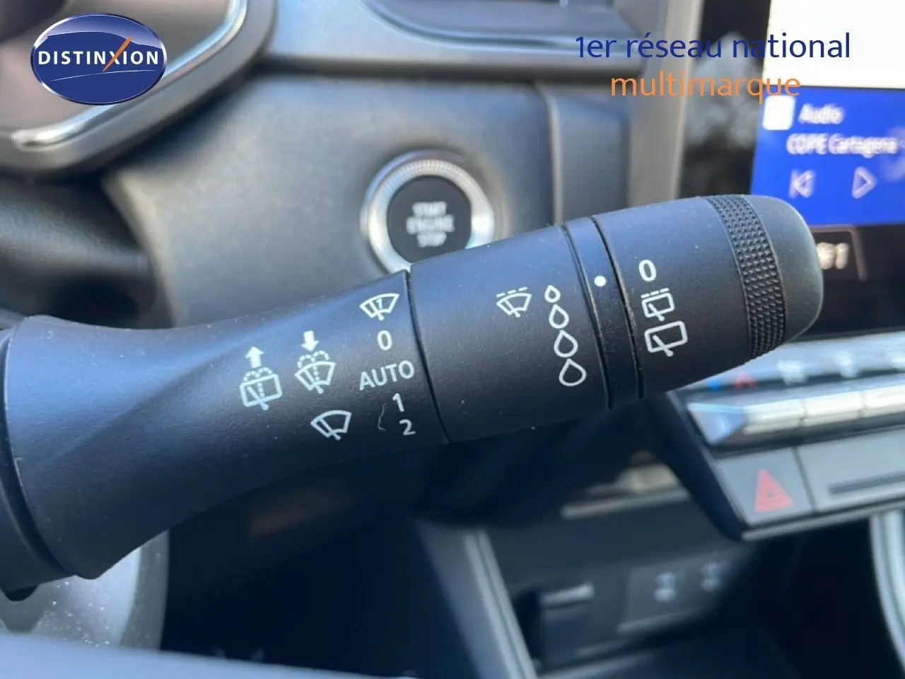 Gros plan sur la commande d’essuie-glace à gauche du volant dans l’habitacle d’un Renault Captur rouge désir métal avec toit noir.