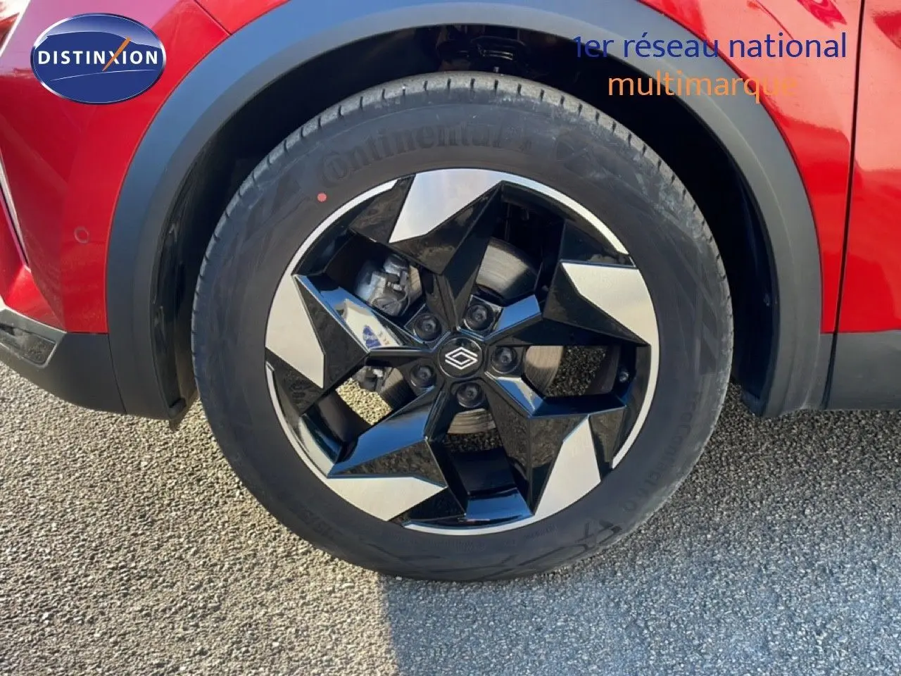 Gros plan sur la roue avant droite du Renault Captur rouge Désir Métal avec jante noire et argentée au design géométrique.