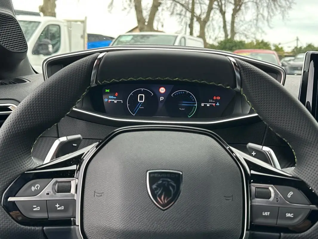 Vue intérieure centrée sur le volant Peugeot 208 gris, avec cockpit numérique et commandes intégrées visibles.