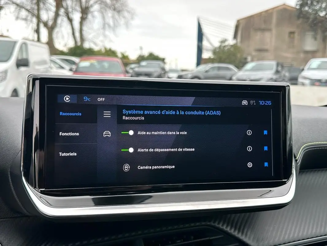 Écran tactile du tableau de bord de la Peugeot 208 Hybrid 110 gris, affichant les aides à la conduite avancées.
