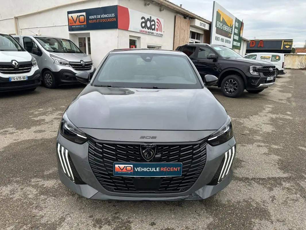 Vue frontale d'une Peugeot 208 Hybrid 110 e-DCS6 GT gris 2025 avec feux LED verticaux et calandre noire distinctive.