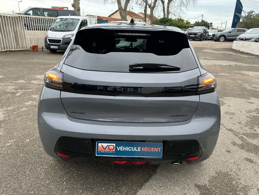 Vue arrière d’une Peugeot 208 Hybrid 110 gris, feux arrière allumés et jantes alliage visibles.