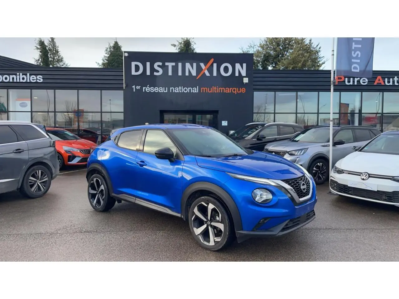 Nissan Juke II bleu magnetic en 3/4 avant droit avec jantes alliage noires devant concession multimarque Distinxion