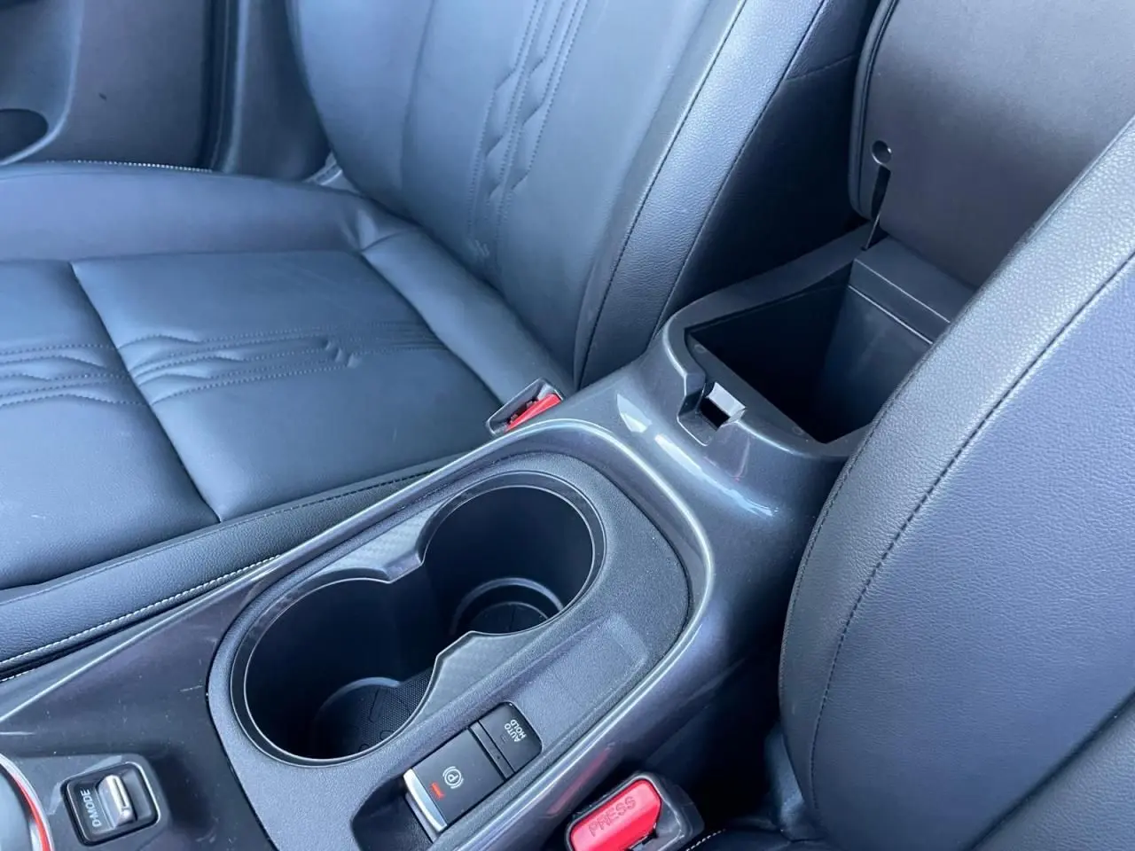 Gros plan sur l'accoudoir central noir et les deux porte-gobelets du Nissan Juke II 2024, sellerie TEP noire.