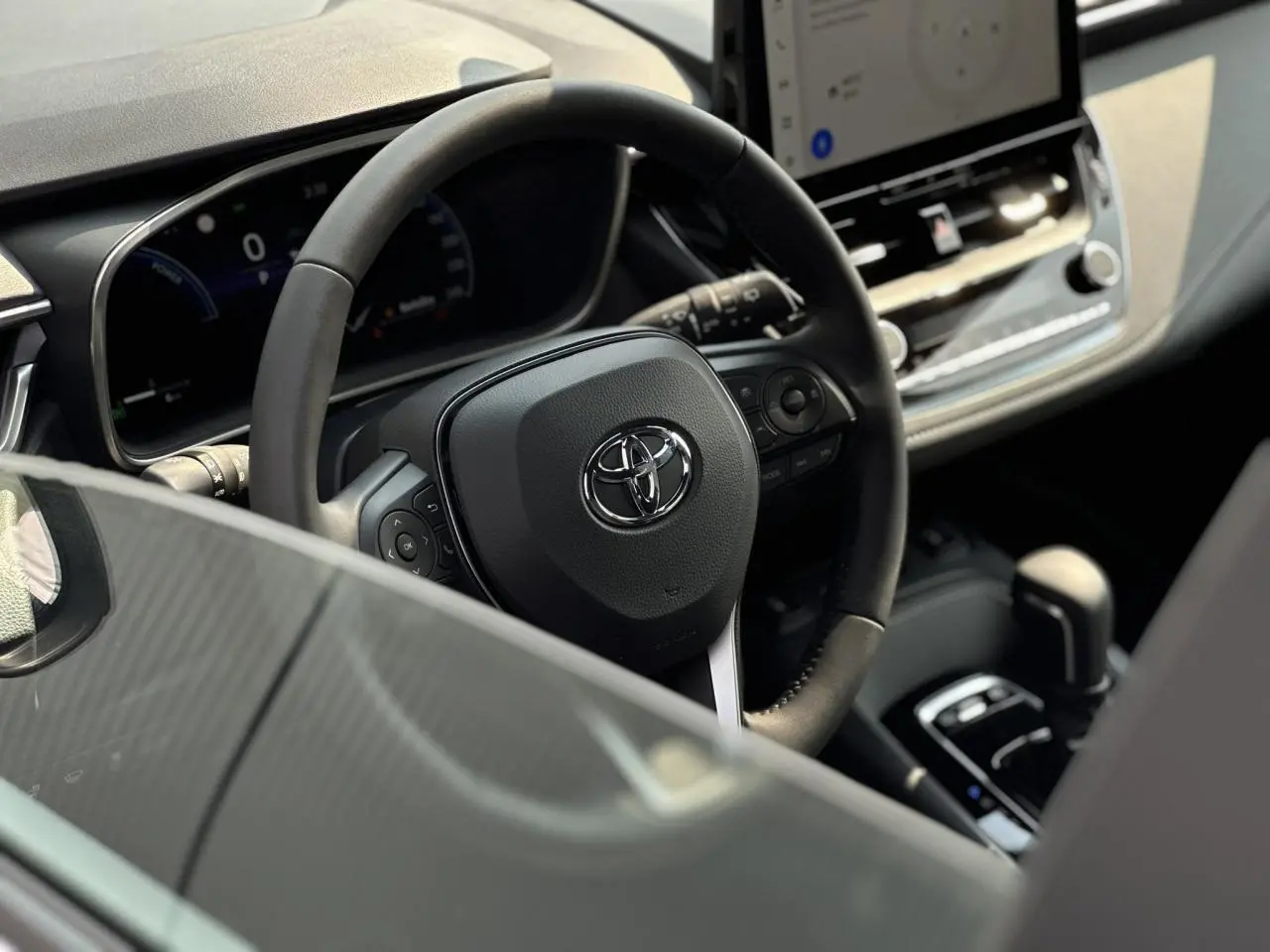 Vue intérieure centrée sur le volant Toyota et la console centrale d'une Corolla Touring Sport blanche avec écran tactile.