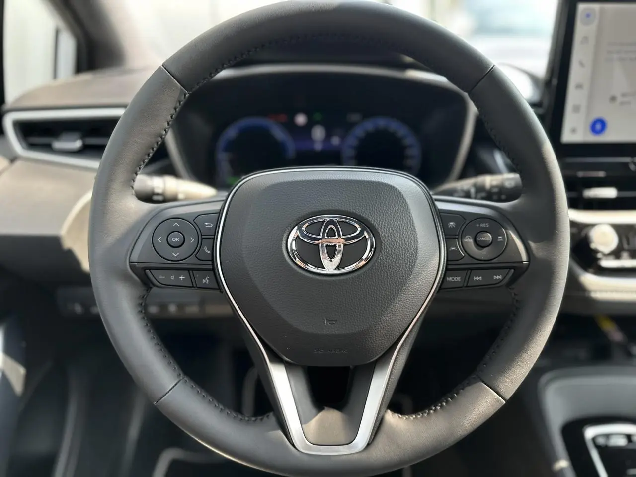 Vue rapprochée du volant multifonction noir avec logo Toyota au centre dans le cockpit de la Corolla Touring Sport 2025.