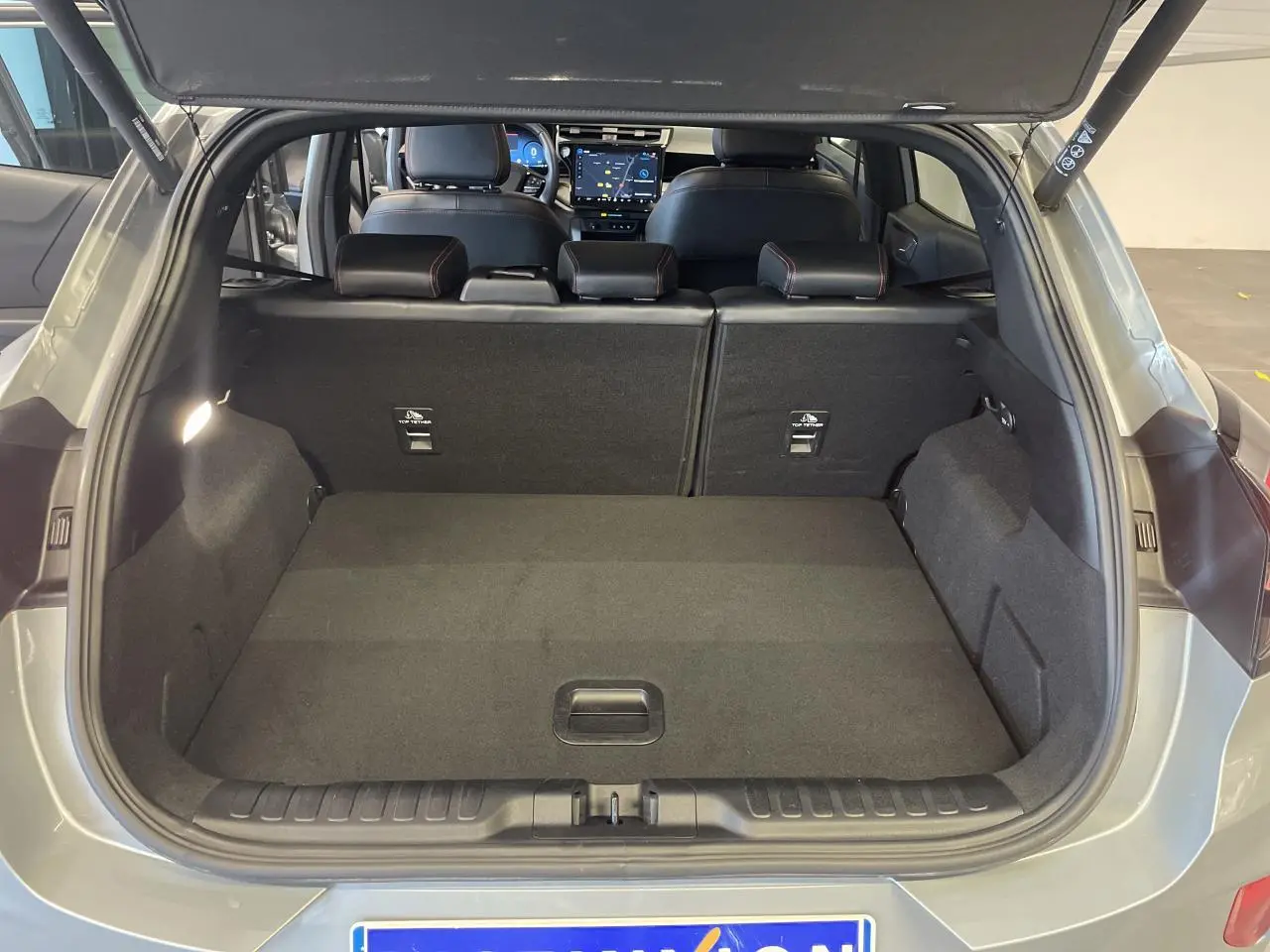 Coffre ouvert vue arrière du Ford Puma gris clair 2024, avec banquette arrière et tableau de bord visible.