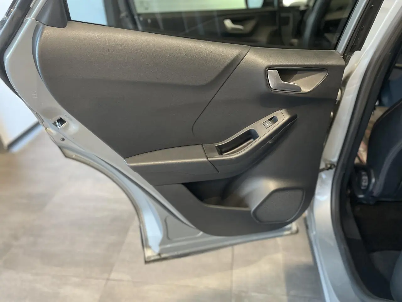 Vue rapprochée de la porte arrière gauche gris clair du Ford Puma 2024, avec poignée et commande de vitre visible.