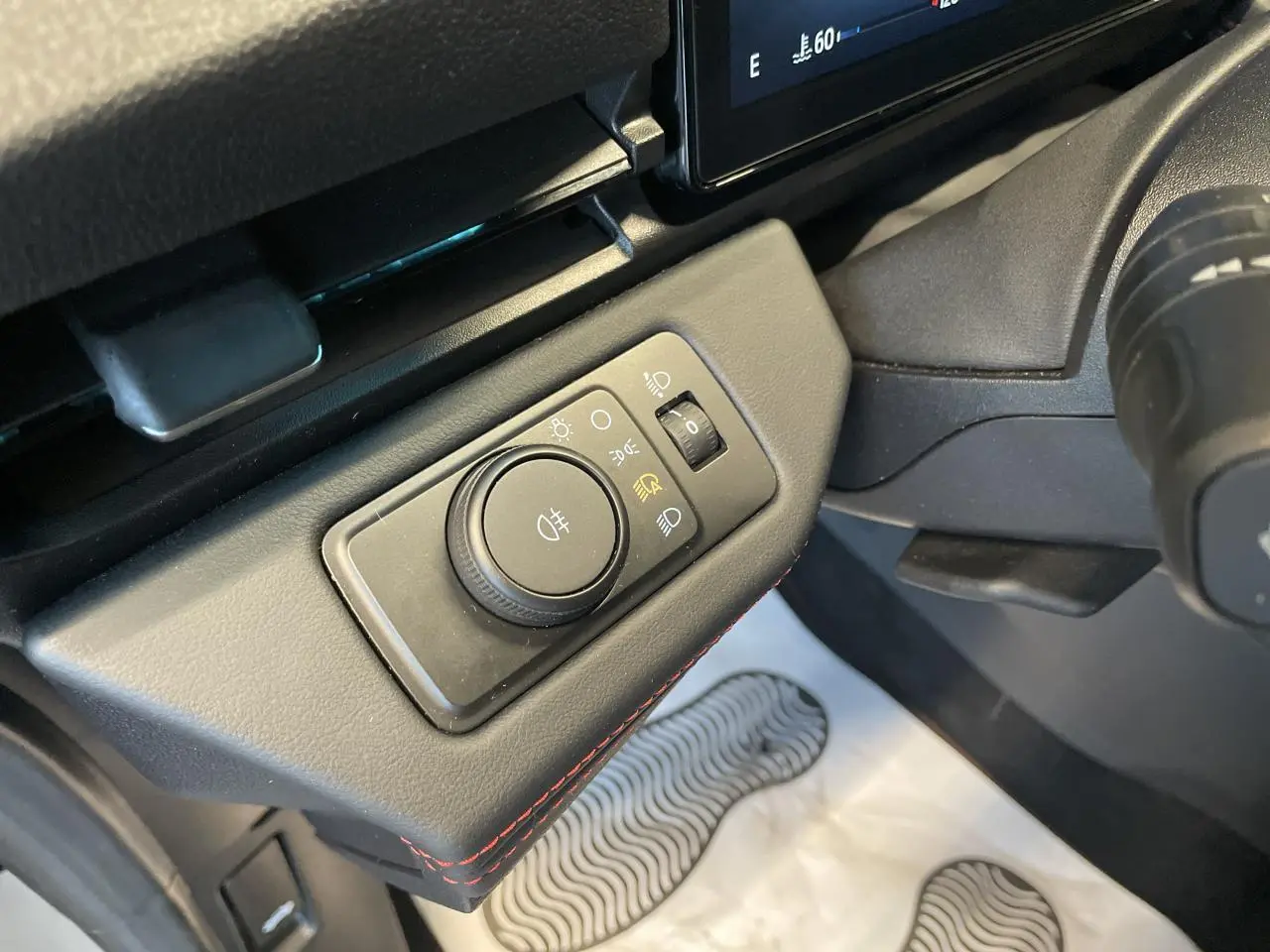Gros plan sur la commande d’éclairage à gauche du volant dans l’habitacle noir du Ford Puma gris clair 2024.