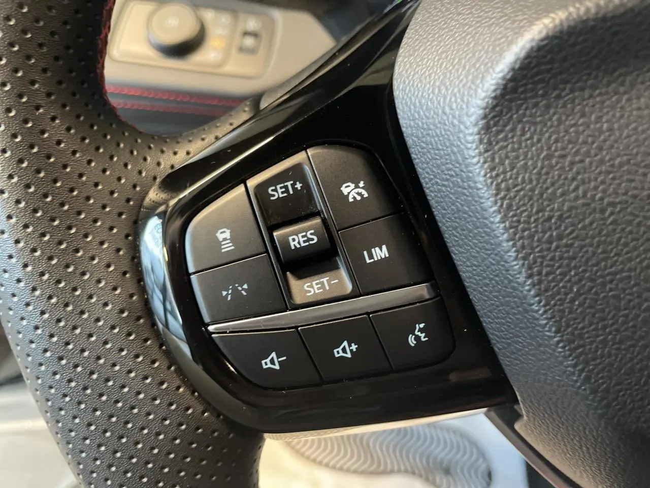 Gros plan sur les commandes du volant perforé noir du Ford Puma 2024, avec boutons de régulateur et volume sonore.