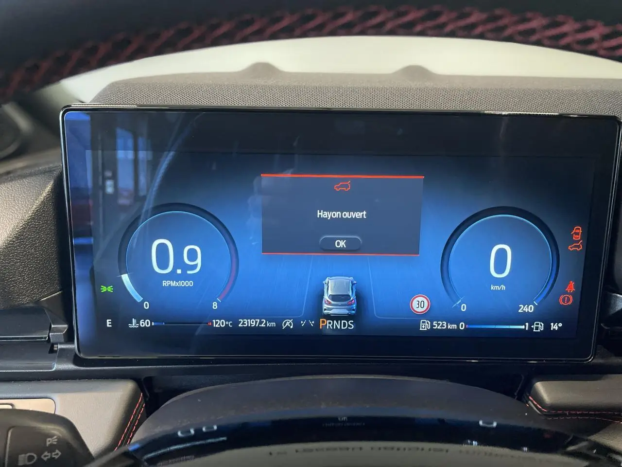 Affichage numérique du tableau de bord du Ford Puma 2024 avec alerte "Hayon ouvert" en vue frontale.