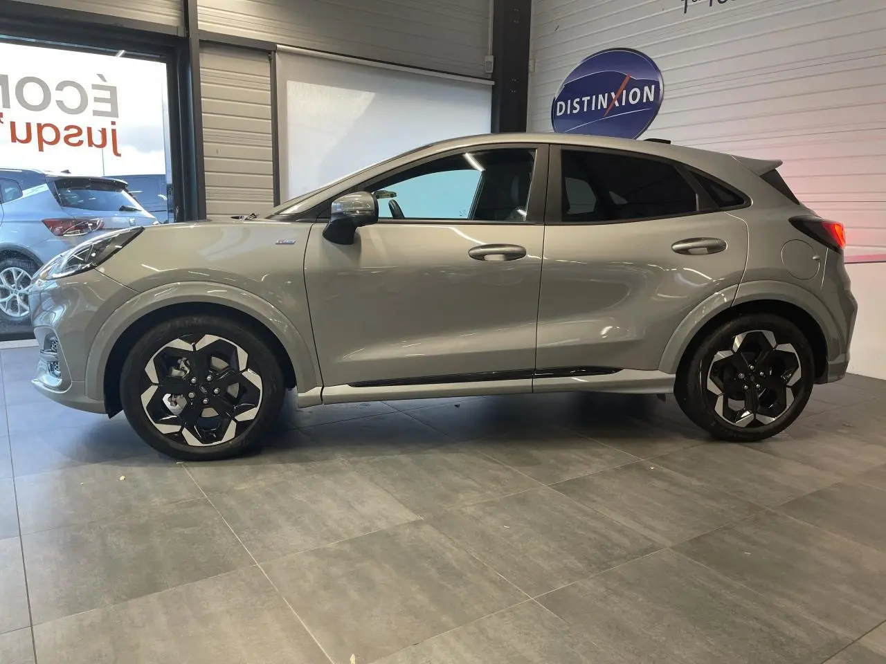 Ford Puma gris clair en vue de profil côté gauche, avec jantes alliage noires et détails ST Line visibles.
